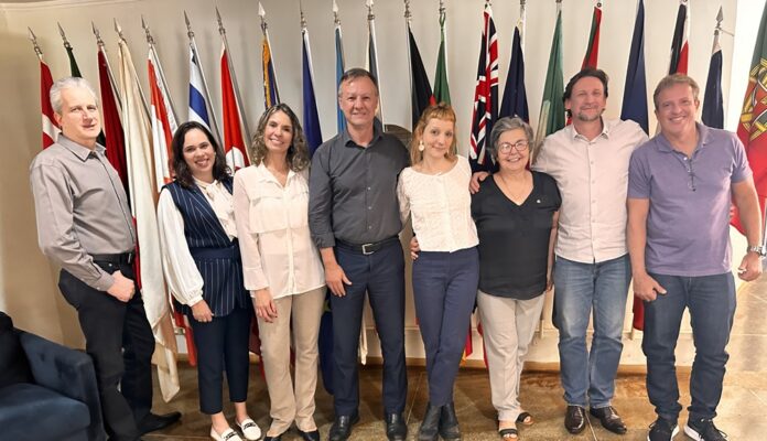 Ao centro da imagem, Ana Luiza Confim Mendes sorri ao lado dos membros do Rotary Club de Brasília Lago Norte, após compartilhar sua inspiradora trajetória em busca da Bolsa Rotary pela Paz.